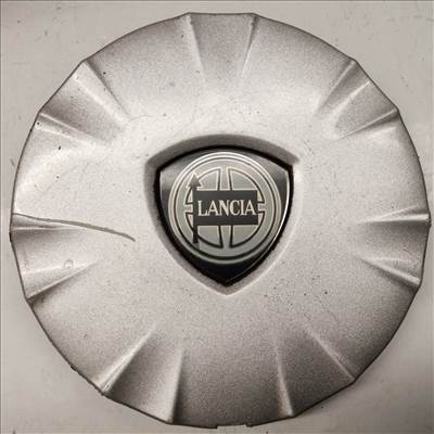 214298 Lancia Ypsilon II. 2003-2011 felni közép kupak, a képen látható állapotban, egy rögzítő fül törött, hiányzik 51708375